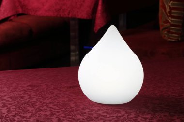 Masanın üzerine bir damla şeklinde beyaz bir lamba.