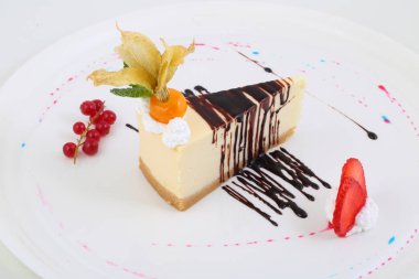 Çilekli cheesecake, frenk üzümü ve bitki salatası beyaz arka planda.