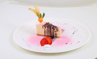 Çilekli cheesecake, frenk üzümü ve bitki salatası beyaz arka planda.