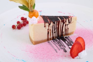 Çilekli cheesecake, frenk üzümü ve çikolata soslu.