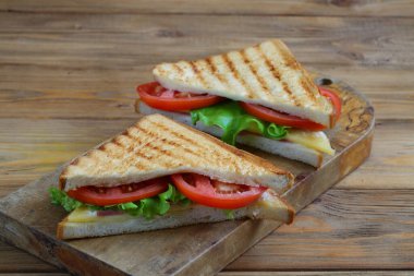 Beyaz arka planda peynirli, domatesli ve jambonlu sandviç.