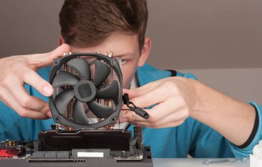 Genç adam oyun anakart üzerinde CPU Soğutucu fan yükleme