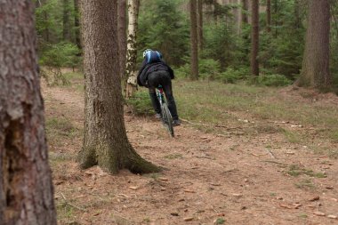 Genç adam ormanın içinden bir dağ bisikleti binme