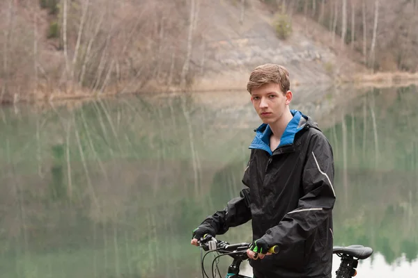 Jeune homme en VTT se détend, sur fond inondé mine — Photo