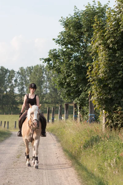 Een jonge vrouw rijden een paard Haflinger — Stockfoto