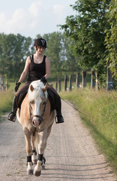 Een jonge vrouw rijden een paard Haflinger — Stockfoto