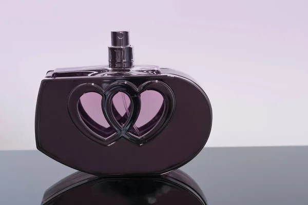 Bottle of perfume in the shape of a heart  on black acrylic shee — Stock Photo, Image