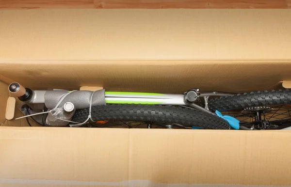 Bike in paper box, photo from unboxing bike. Saddle, front wheel