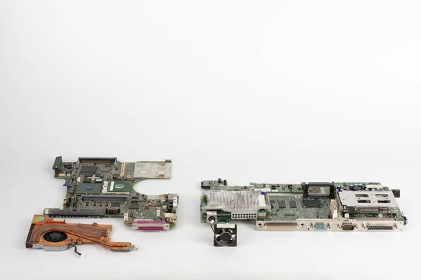 Comparing two laptop mother boards  with fans, one with orange fan from 2003, one from 1999.