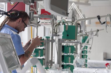 Erkek hemşire hastanedeki yoğun bakımda şırınga enjeksiyon pompasının işlevini kontrol ediyor.. 