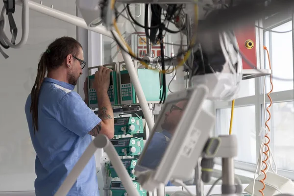 Male nurse checks the function of infusion pump in ICU in hospital.