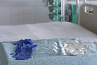 Üç çift eldiven, üç plastik koruyucu gözlük ve hastanedeki yoğun bakımdaki masada üç solunum cihazı var. Virüse karşı korunmak için kişisel koruyucu ekipmanlar..