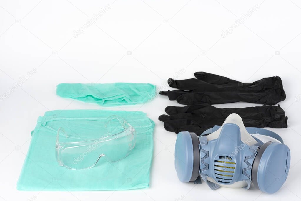 Twin filter half face respirator mask, plastic protective eyglasses, protective gown, cap, pair of gloves,  personal protective equipment to protect against the virus covid-19.