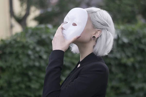 Uma jovem loira a tirar uma máscara. Fingindo ser outro conceito. exterior . Fotos De Bancos De Imagens