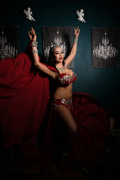 Sexy slim woman, belly dancer in red costume with crystals. Dark background ロイヤリティフリーのストック画像