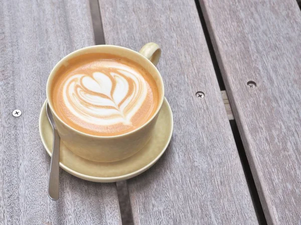 Taza de café en la mesa de madera con arte latte . — Foto de Stock