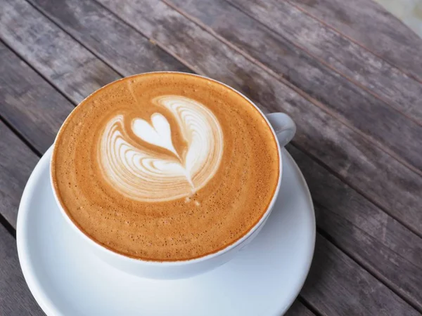 Taza de café en la mesa de madera con arte latte . — Foto de Stock