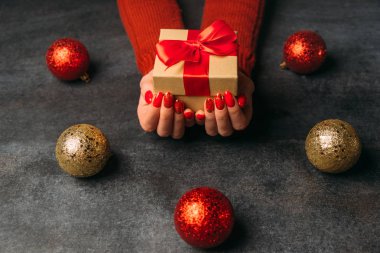 Kadın eli kırmızı fiyonklu Noel hediyesi kutusu.