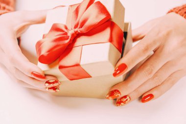 Moda kırmızı manikürlü bir kadın eli hediye kutusunu açıyor..