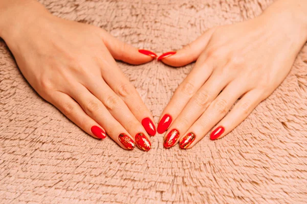 Jonge vrouwelijke handen met rode manicure op zacht oppervlak. — Stockfoto