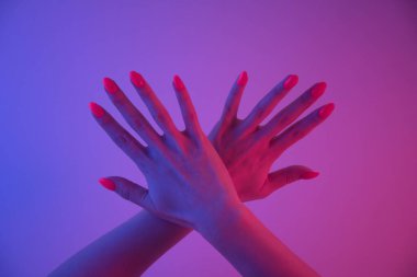 Parlak turuncu manikürlü, son moda neon ışığı olan kadın elleri. Canlı bir renk. Disko biçimi.