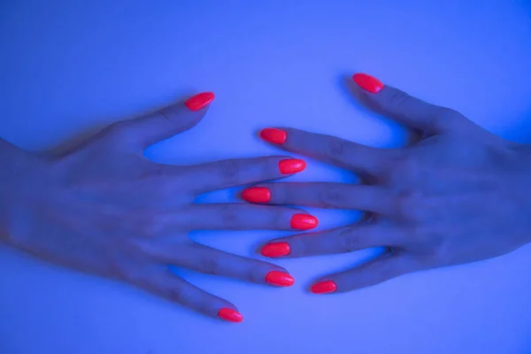 Mãos Mulher Com Manicure Laranja Vívida Luz Azul Neon Cor — Fotografia de Stock