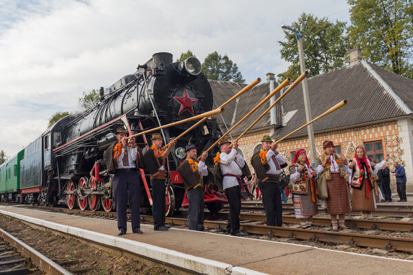 Yasynya, Ukraine - September 29, 2016: Musicians in national dress posing against the backdrop of the old steam locomotive