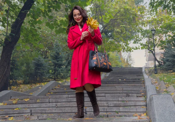 Hermosa mujer con un abrigo rojo bajando las escaleras. Gente — Foto de Stock