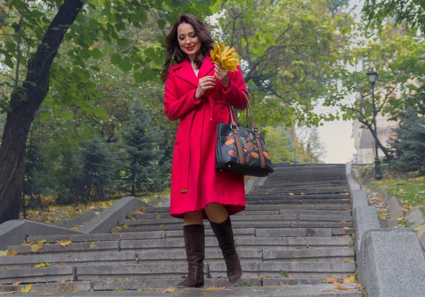 Beautiful woman in a red coat walking down the stairs. People — Stock Photo, Image