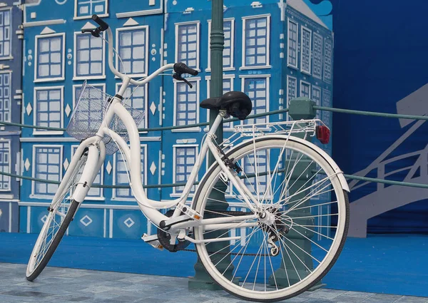Λευκό ποδηλάτων με ένα καλάθι σταθμευμένα έξω από το τοπίο της πόλης. — Φωτογραφία Αρχείου