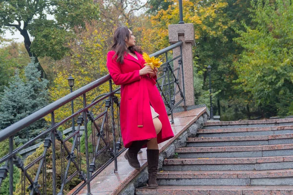Hermosa mujer en un abrigo rojo mirando hacia atrás mientras está de pie en una l — Foto de Stock