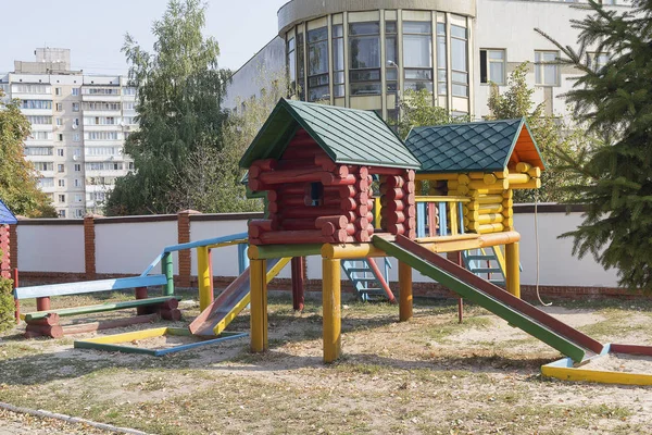 Барвистий дерев'яний будинок з повзунком на порожньому дитячому майданчику. Місто — стокове фото