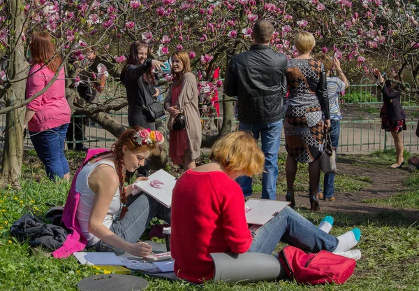 Kiev, Ukraina - 14. april 2016: Jenter i hagen trekker fra naturen blomstrende magnoliaer – stockfoto