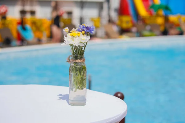 Цветы на столе на фоне крупного плана бассейна — стоковое фото
