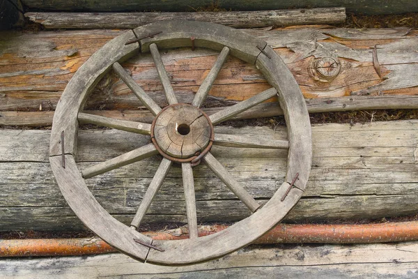 Roda de madeira de um carro antigo pendurado na parede da cabana — Fotografia de Stock