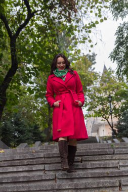 Merdivenlerden aşağı yürüyüş kırmızı paltolu güzel bir kadın. İnsanlar