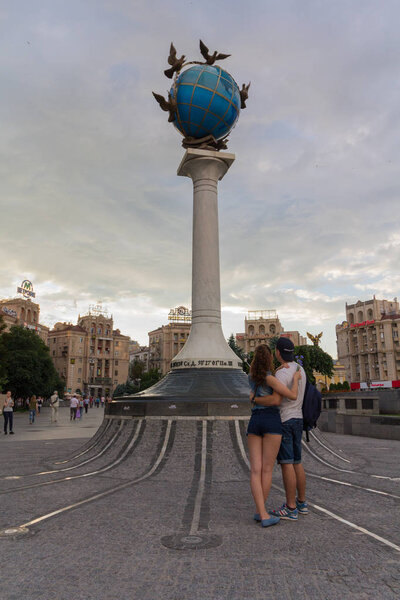 Киев, Украина - 16 июня 2016 года: Молодая пара на свидании с памятником с глобусом
