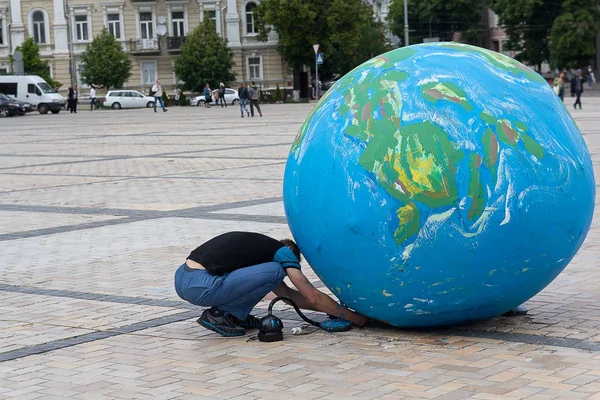 L'homme sur la place de la ville souffle un modèle de la planète Terre — Photo