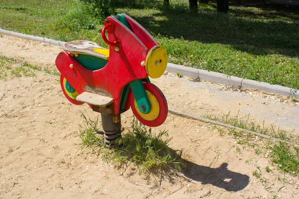 Una motocicleta roja de madera, un columpio. Parque infantil — Foto de Stock