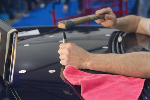 Hände des Meisters bei den Arbeiten zum Richten der Motorhaube. Industrie — Stockfoto