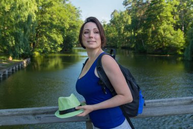 Güzel kadın bir şapka ve bir sırt çantası bridge Park. İnsanlar