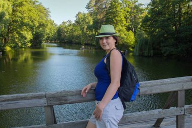 Güzel kadın bir şapka ve bir sırt çantası bridge Park. İnsanlar