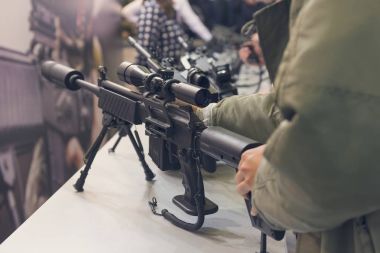 Tezgahta otomatik tüfekli bir adam var. Silahlar.