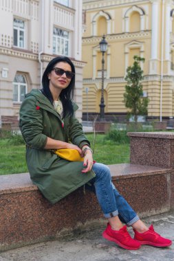 Kırmızı spor ayakkabılar basamaklarında oturan güzel kadın. İnsanlar