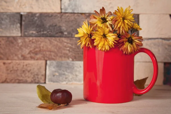 Flores amarillas en taza roja en la mesa de la cocina. Bodegón — Foto de Stock