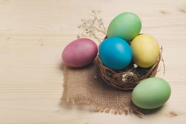 Färgade ägg i en korg på en yta av trä. Påsk stilleben — Stockfoto