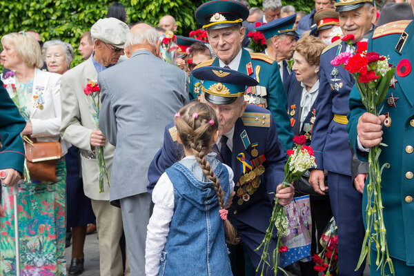 Kiev, Ukraine - May 9, 2016: Girl gives flowers to the veterans of the Great Patriotic War in the park of eternal glory