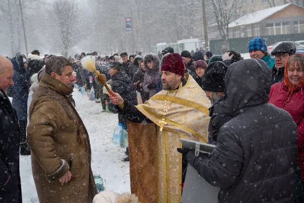 Киев, Украина - 18 января 2018 года: Священник окропляет прихожан храма освященной водой на праздновании православного праздника Богоявления — стоковое фото