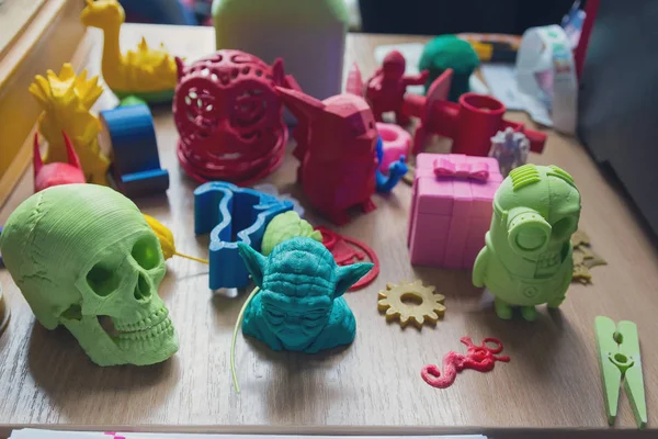 Διάφορα μοντέλα πλαστικού στο τραπέζι κατασκευάζονται σε έναν εκτυπωτή 3D. Τεχνολογία — Φωτογραφία Αρχείου