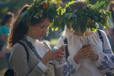 Kiev, Ukraine - July 06, 2017: Girls in wreaths from flowers with smartphones at the celebration of a traditional Slavic holiday of Ivan Kupala clipart